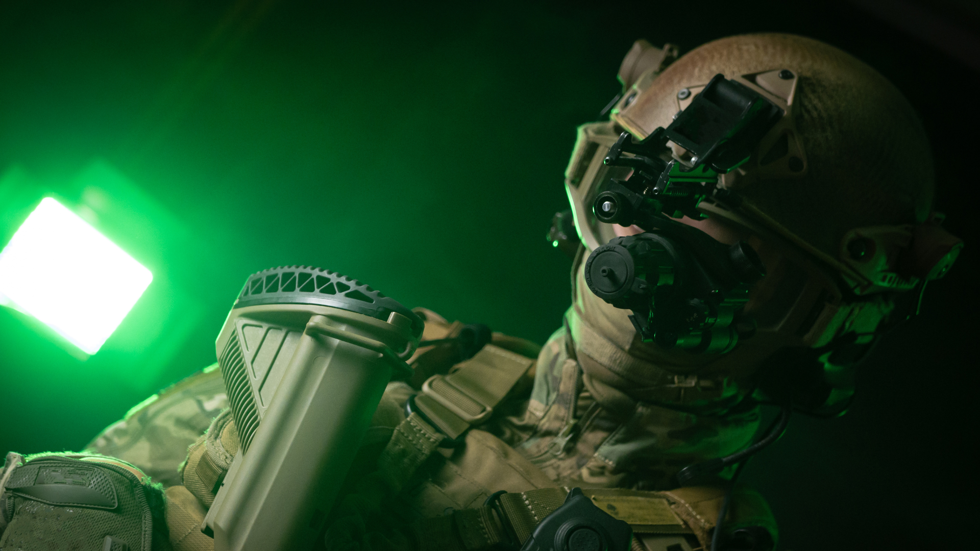 a soldier in military clothing with a night vision device and on a dark background